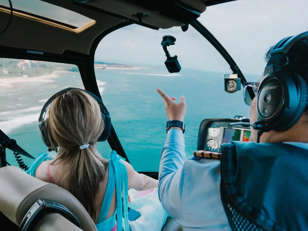 Helicopter transfer over the Bali coastline with pilot and passenger